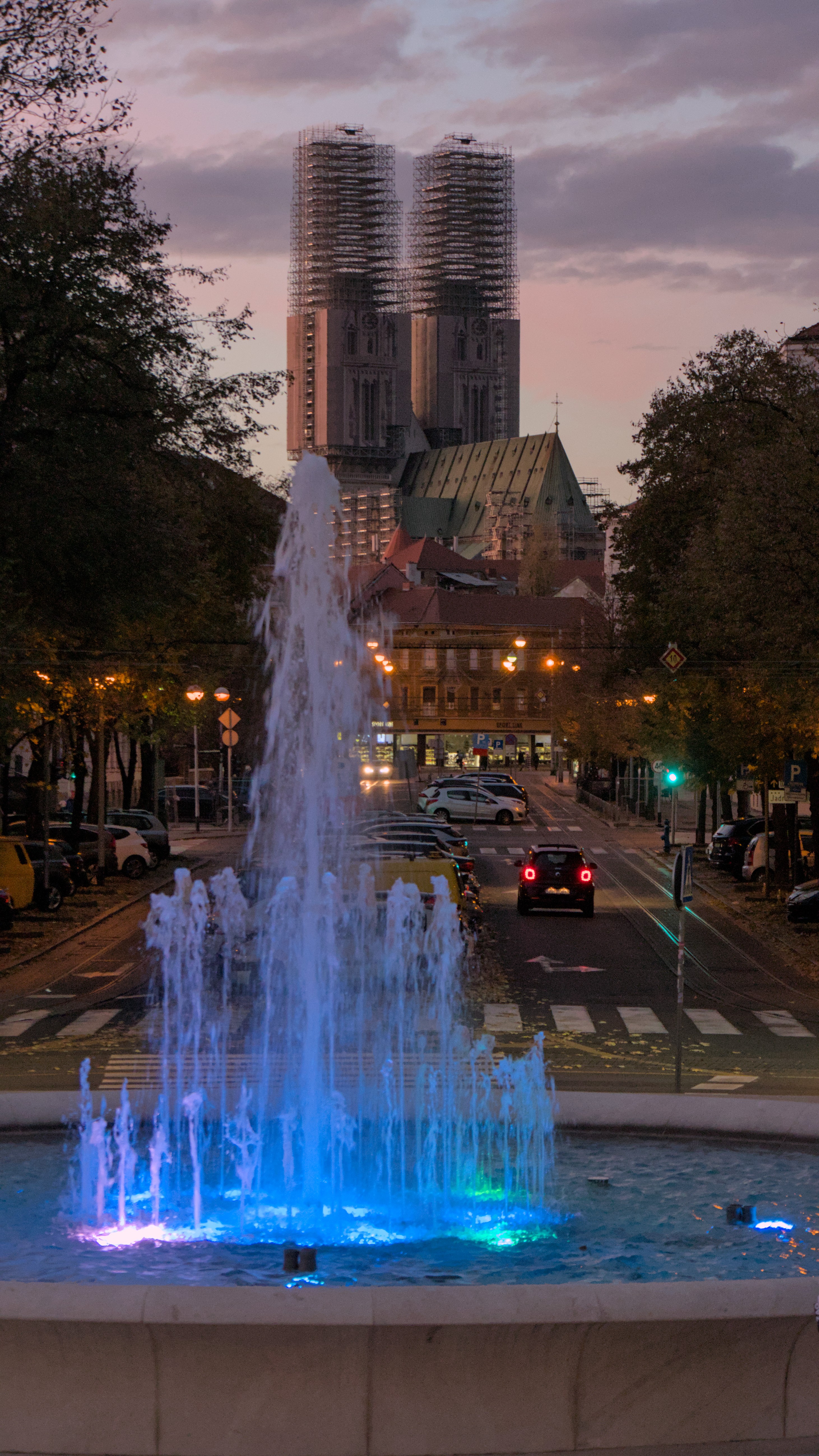 The cathedral of Zagreb behind a fountain illuminated by blue lights.